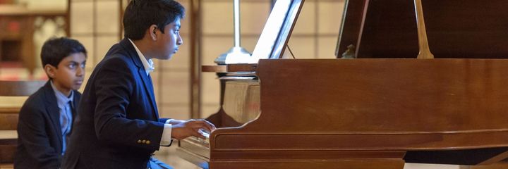 A high school student plays piano in a recital